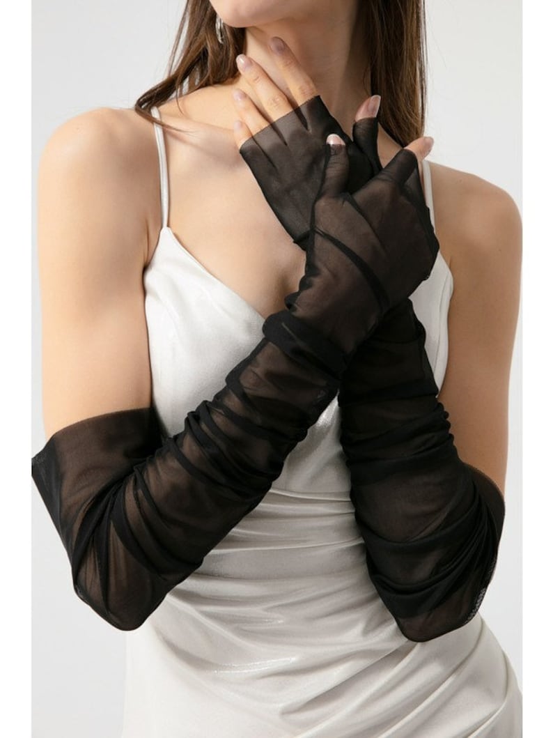 May include: Black sheer long gloves with a gathered detail. The gloves are fingerless and extend to the elbow.