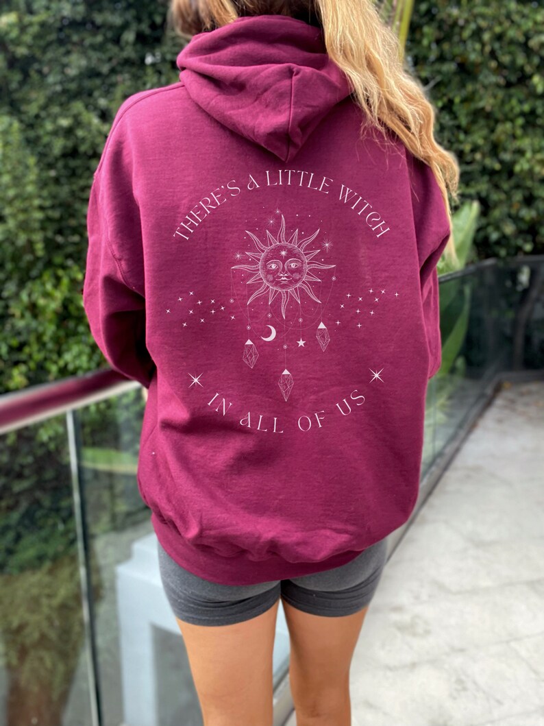 Puede incluir: Sudadera con capucha burdeos con la inscripci&oacute;n blanca "THERE'S A LITTLE WITCH IN ALL OF US". El dise&ntilde;o presenta un sol, estrellas, lunas y cristales. La sudadera es de color liso y tiene un corte holgado.
