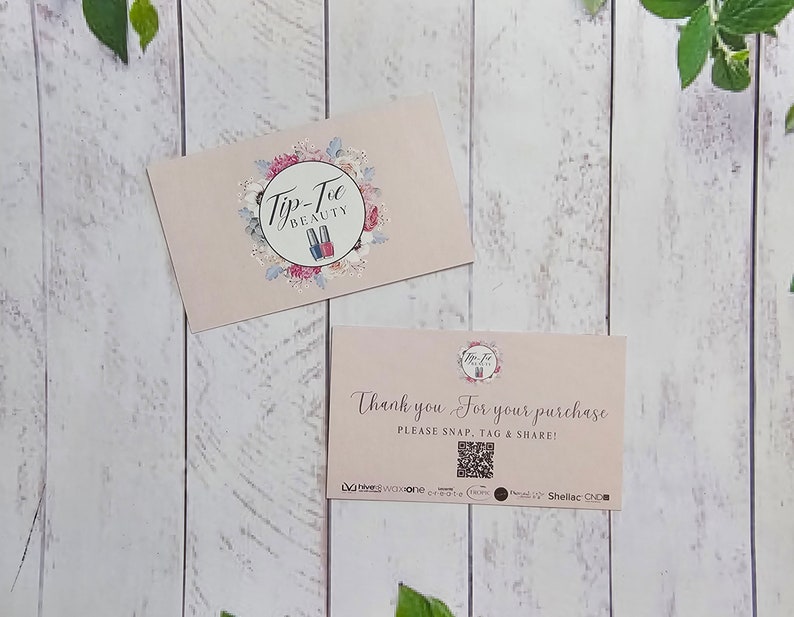 May include: Two pink business cards with a floral design. The top card has the text "Tip-Toe Beauty" and a logo of two nail polish bottles. The bottom card says "Thank you for your purchase. Please snap, tag & share!" and has a QR code.