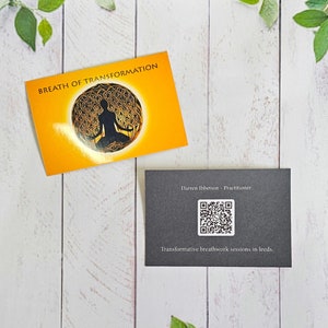 May include: Two business cards on a white wooden background. The top card is orange with the text "Breath of Transformation" and a black silhouette of a person meditating inside a circle. The bottom card is black with the text "Darren Ibbetson - Practitioner" and a QR code. The text "Transformative breathwork sessions in Leeds" is below the QR code.