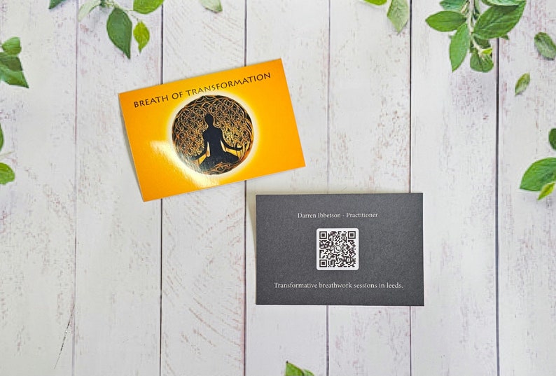 May include: Two business cards on a white wooden background. The top card is orange with the text "Breath of Transformation" and a black silhouette of a person meditating inside a circle. The bottom card is black with the text "Darren Ibbetson - Practitioner" and a QR code. The text "Transformative breathwork sessions in Leeds" is below the QR code.