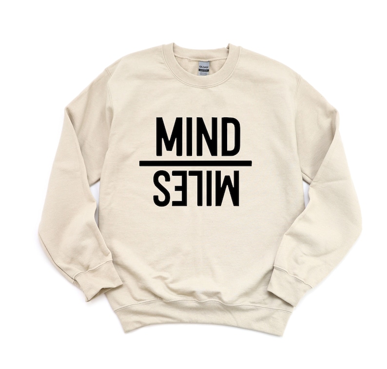 May include: A beige sweatshirt with black text that reads "MIND OVER MILES".