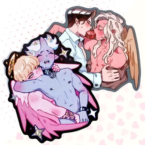 Puede incluir: Dos juegos de pegatinas con ilustraciones de parejas. Una pegatina muestra un demonio de piel azul con cuernos y un halo sosteniendo un ángel rubio con alas. La otra pegatina muestra a un hombre con cabello castaño besando a un hombre con cabello rubio y alas.