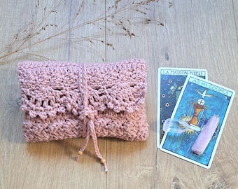 May include: A dusty rose crochet pouch featuring a scalloped flap and a tie closure with small wooden beads. The pouch is positioned next to two tarot cards, one labelled La Maison-Dieu and the other As des Coupes, along with a clear crystal point.