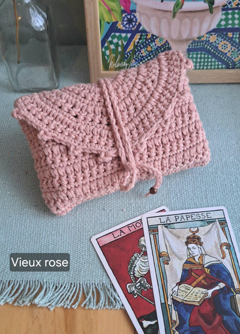 May include: A dusky pink crochet pouch with a flap and drawstring closure. Two tarot cards are next to the pouch, one with a skeleton and the other with a crowned woman. The image includes the text "Vieux rose".