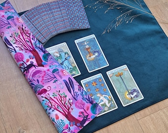 May include: A dark teal velvet tarot cloth featuring a pink fabric overlay with a forest pattern of trees, mushrooms, and rabbits. Four tarot cards are laid out, including La Temperance, As des Coupes, L'Etoile, and As des Epees, with a deck.