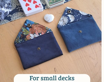 May include: Two envelope-style pouches with snap closures. One pouch features a dark blue exterior with a floral interior lining. The second pouch has a dark blue exterior with a celestial moon and star patterned interior lining. Text reads: For small decks.