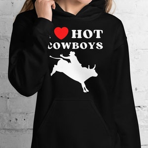 May include: Black hoodie with a white silhouette of a cowboy riding a bull. The text "I ♥ HOT COWBOYS" is printed on the hoodie.