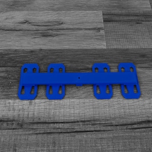 May include: A blue plastic strap with multiple holes and a center bar. The strap is designed to be used for securing items.