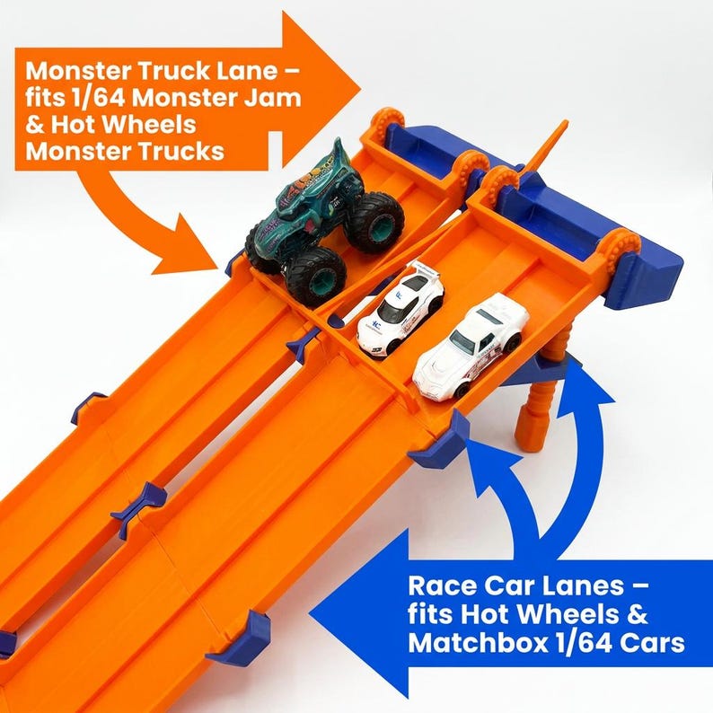 K&ouml;nnte beinhalten: Eine orangefarbene und blaue Spielzeug-Rennstrecke mit drei Fahrspuren. Auf der Strecke steht "Monster Truck Lane" und "Race Car Lanes". Ein gr&uuml;ner Monstertruck und zwei wei&szlig;e Rennwagen befinden sich auf der Strecke.