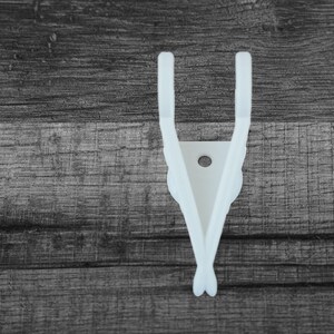 Puede incluir: Un colgador de guitarra blanco, impreso en 3D, para montar en la pared. El colgador presenta un dise&ntilde;o &uacute;nico con dos brazos curvos y un soporte central con un agujero. El dise&ntilde;o recuerda a alas. El colgador est&aacute; dise&ntilde;ado para sujetar una guitarra.