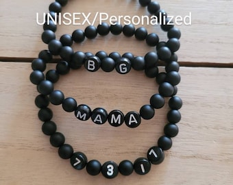 May include: Three black beaded bracelets with white lettering. The top bracelet spells "BG", the middle bracelet spells "MAMA", and the bottom bracelet spells "731".