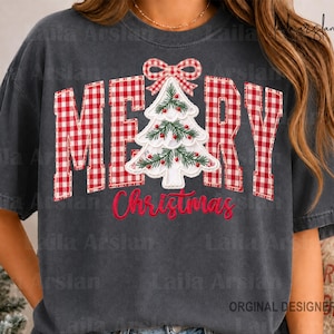 Może przedstawiać: Ciemnoszary t-shirt z krótkim rękawem z napisem MERRY w czerwono-białą kratkę, gdzie literę E zastępuje biała, haftowana choinka. Słowo Christmas jest nadrukowane czerwoną kursywą poniżej choinki.