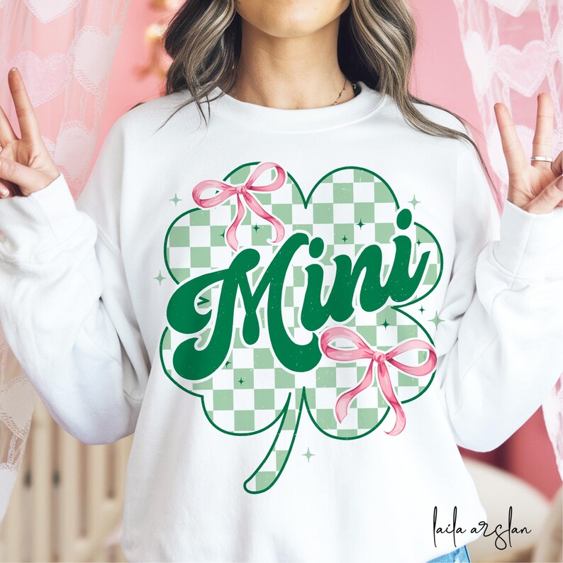 May include: White sweatshirt with a green shamrock design and the word "Mini" in a retro font. The shamrock has a checkered pattern and pink bows.