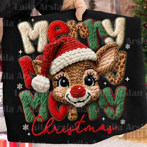 May include: A black Christmas-themed decorative pillow featuring a reindeer wearing a Santa hat. The words "Merry Christmas" are embroidered in red, green, and cream-colored yarn, with snowflakes and plus signs as accents.
