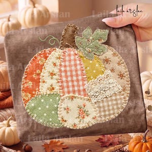 May include: A brown fabric square featuring a central pumpkin applique made from various patterned fabric patches including orange floral, white and orange gingham, green polka dot, and cream lace, all secured with visible blanket stitching.