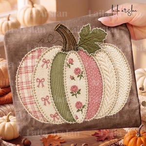 May include: A square brown fabric panel featuring a large pumpkin appliqué made of various textured patches. The pumpkin includes sections of plaid, solid green corduroy, floral print, pink polka dots, and cream cable knit, finished with a green leaf.