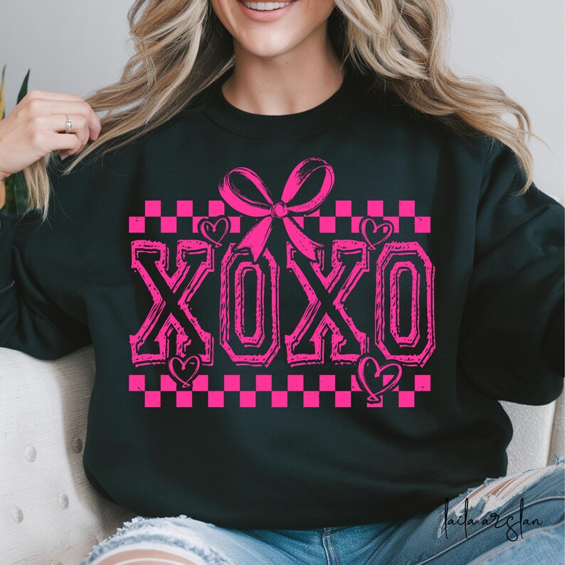 Puede incluir: Sudadera negra con un patr&oacute;n de cuadros rosas, un lazo rosa y la palabra "XOXO" en letras rosas.