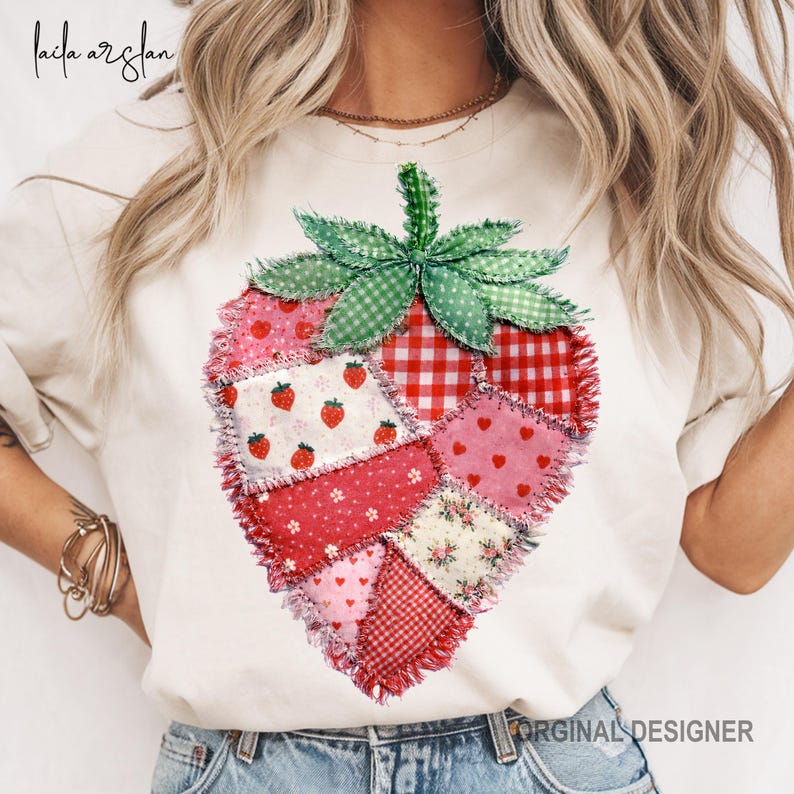May include: Cream-colored t-shirt featuring a patchwork strawberry design. The strawberry is composed of various fabric patterns, including red gingham, floral, and polka dots. The strawberry has a green stem and leaves. The text "ORIGINAL DESIGNER" is at the bottom.