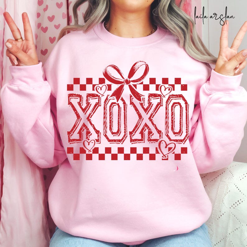 Puede incluir: Sudadera rosa con un patr&oacute;n de cuadros rojos y un lazo rojo con el texto "XOXO" en rojo.