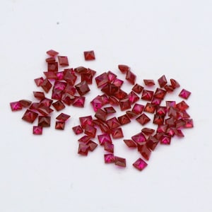 Könnte beinhalten: Eine Sammlung loser, quadratischer Edelsteine in Rot.