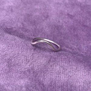 May include: A silver ring with a curved, wave-like design.