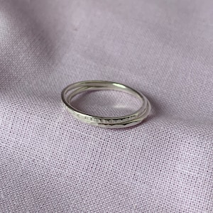 May include: Two silver rings stacked on top of each other. The rings are textured and have a hammered finish.