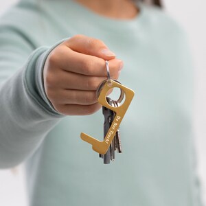 May include: A gold-colored key chain with a tool for opening doors without touching the handle. The tool is engraved with the words "Do Not Touch".