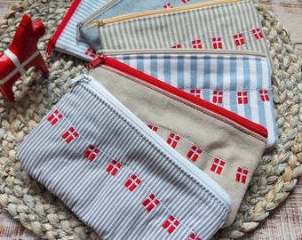 May include: A set of six zippered pouches with a striped pattern and red Danish flag embroidery. The pouches are made of a soft, textured fabric and are perfect for storing small items.