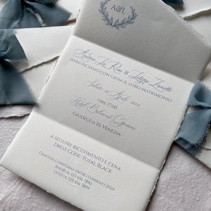 May include: A wedding invitation with a white background and blue text. The invitation announces the marriage of Andrea La Rosa and Lettizia Lanolle on Saturday, April 20, 2024 at 5:00 PM at the Hotel Belmond Cipriani in Venice, Italy. The invitation also includes the dress code: Total Black.