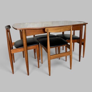 May include: A rectangular wooden dining table with rounded corners and four matching chairs. The table and chairs feature a medium-brown wood finish. Each chair has a curved backrest and a seat upholstered in smooth black material.