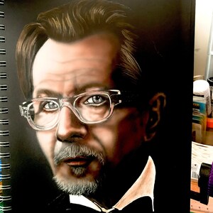 Puede incluir: Un dibujo en blanco y negro de un hombre con barba y gafas. El hombre lleva una camisa blanca de cuello y una pajarita negra. El dibujo está hecho sobre un fondo negro.