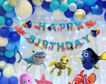 May include: A festive birthday party scene with blue and white balloons, a banner that says "Happy Birthday", and various cartoon sea creatures. The decorations include a shark, turtle, and fish.