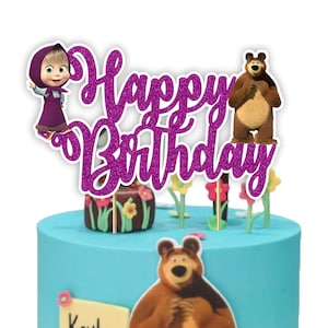 May include: A cake topper with the words "Happy Birthday" in glittery purple script. The topper features cartoon characters Masha and the Bear. The cake is light blue with a brown bear graphic and floral decorations.