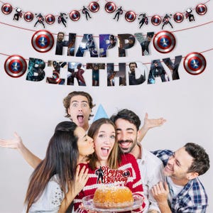 Pu&ograve; includere: Un festoso striscione di compleanno con scudi e ritagli di personaggi di Captain America. Lo striscione recita "BUON COMPLEANNO" con immagini di personaggi. Un gruppo di persone festeggia con una torta.