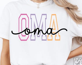 May include: White t-shirt with the word "OMA" in a colorful, block letter design. The word "oma" is written in a cursive font. The shirt is a casual style, suitable for everyday wear.