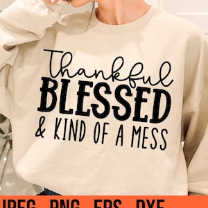 Puede incluir: Una sudadera beige con el texto "Thankful Blessed & Kind of a Mess" impreso en negro.