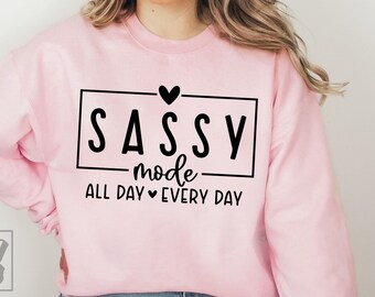 May include: Pink sweatshirt with black text that reads "SASSY mode ALL DAY EVERY DAY" with a heart symbol between "ALL DAY" and "EVERY DAY".