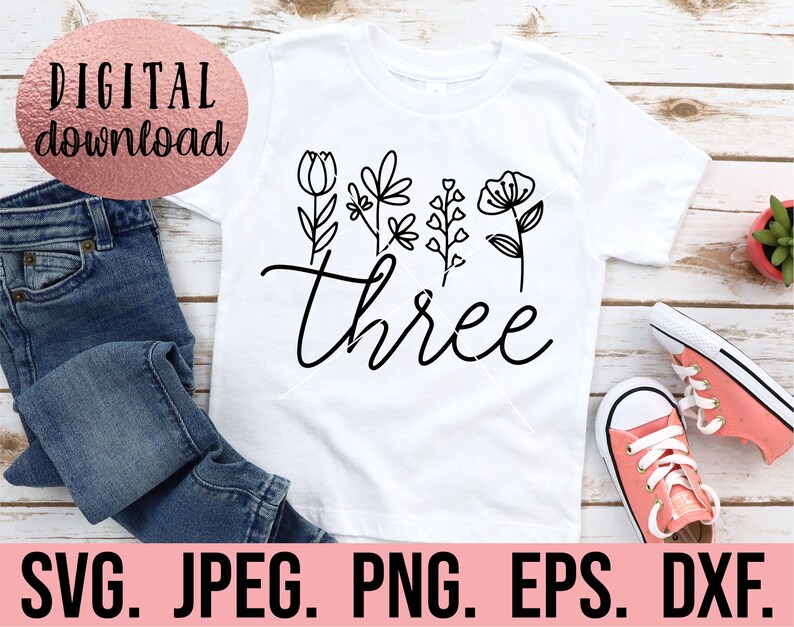 May include: White t-shirt with black floral designs and the word "three" in a cursive font.
