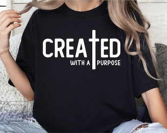 以下が含まれることがあります： 白い文字で「CREATED WITH A PURPOSE」と十字架が書かれた黒いTシャツ
