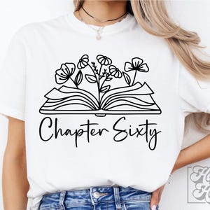 Peut inclure: T-shirt blanc avec un contour noir d'un livre ouvert avec des fleurs qui en poussent. Le texte "Chapter Sixty" est sous le livre.