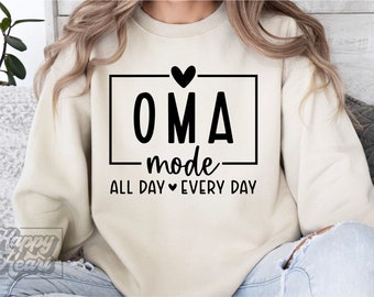 May include: A cream-colored sweatshirt with black text that reads "OMA mode ALL DAY EVERY DAY" with a small heart symbol between "ALL DAY" and "EVERY DAY".