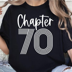 May include: Black t-shirt with white text that reads "Chapter 70". The number 70 is in a retro style with white stripes.