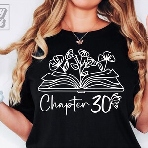 May include: Black t-shirt with a white outline of an open book with flowers growing from it. The text "Chapter 30" is below the book with a butterfly to the right of the number.