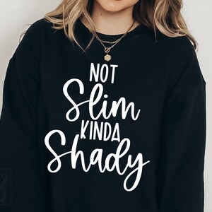 May include: Black sweatshirt with white text that reads "Not Slim Kinda Shady".