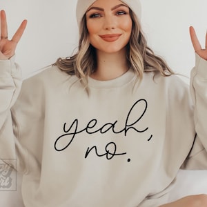 Pode incluir: Uma camisa de moletom bege com o texto "yeah, no." escrito em caligrafia preta.