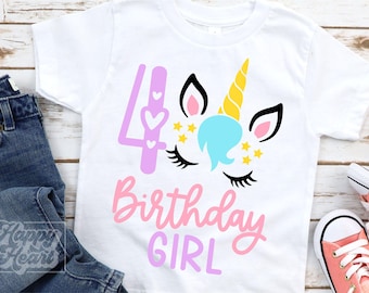 May include: White t-shirt with a colorful unicorn design and the text "4 Birthday Girl". The unicorn has a yellow horn, blue mane, and pink ears. The shirt is paired with blue jeans and pink sneakers.
