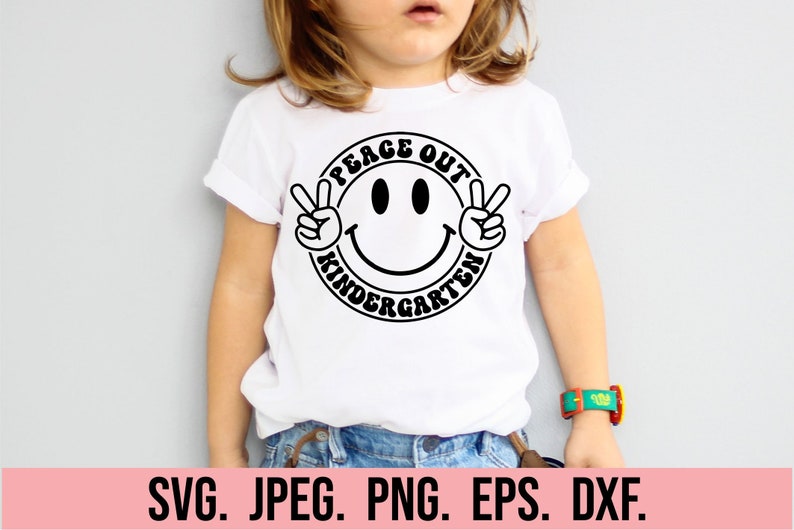 May include: A white t-shirt with a black peace sign and smiley face graphic. The graphic says "Peace Out Kindergarten".
