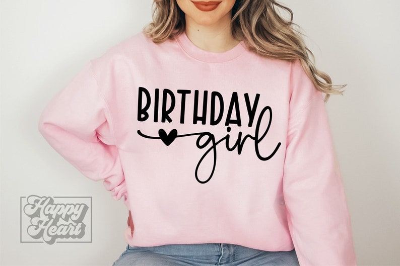 Pode incluir: Camisola cor-de-rosa com o texto "birthday girl" em letras pretas com um pequeno cora&ccedil;&atilde;o.