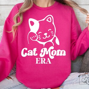 May include: A pink sweatshirt with a white cartoon cat and the text "Cat Mom ERA" in white.